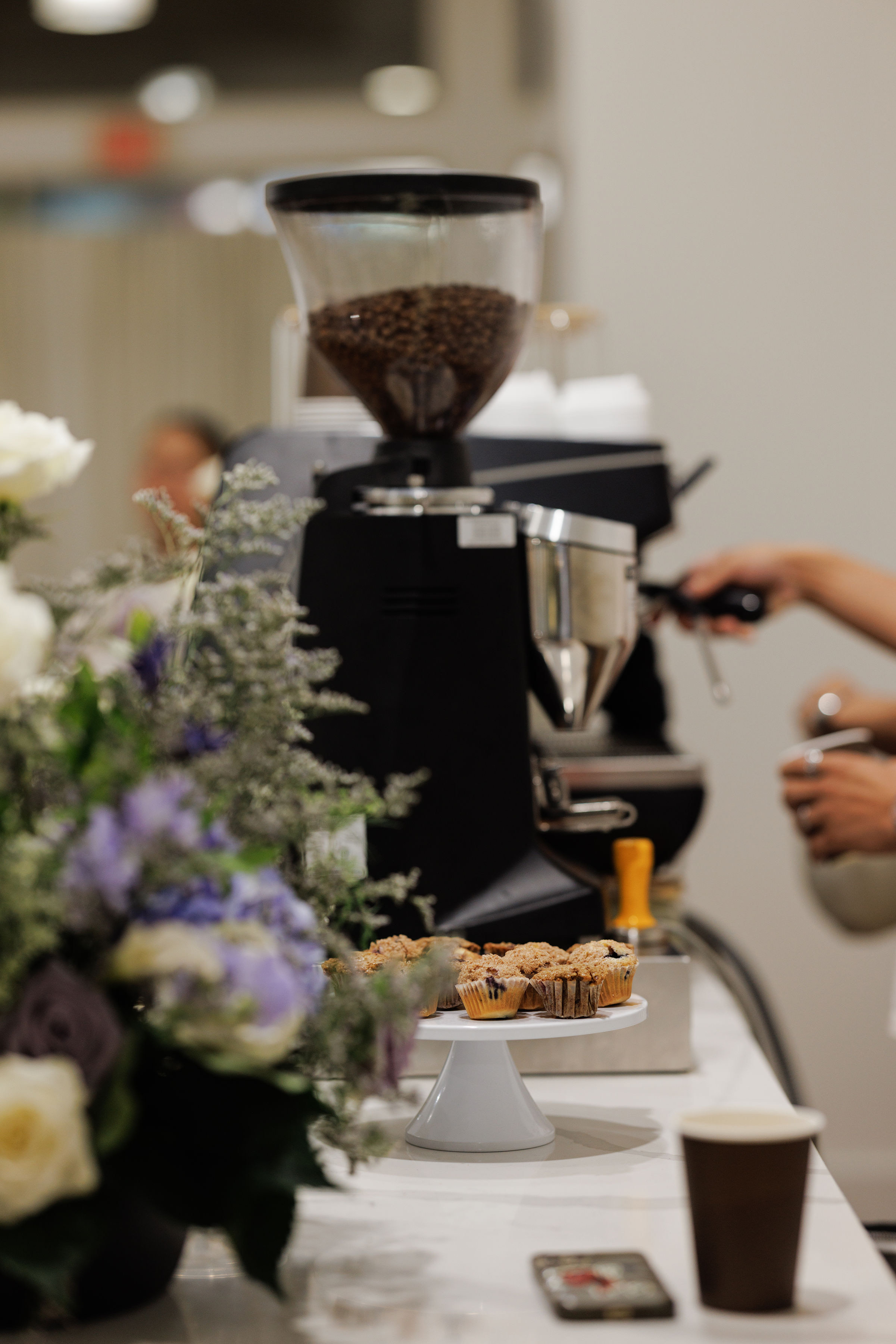 Espresso grinder with flowers and muffins at event